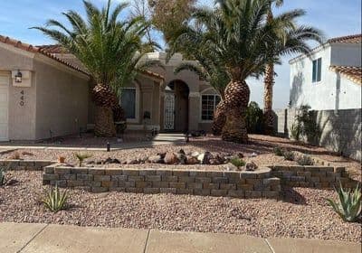 Desert landscape home with palm trees, rock garden, and decorative stonework.