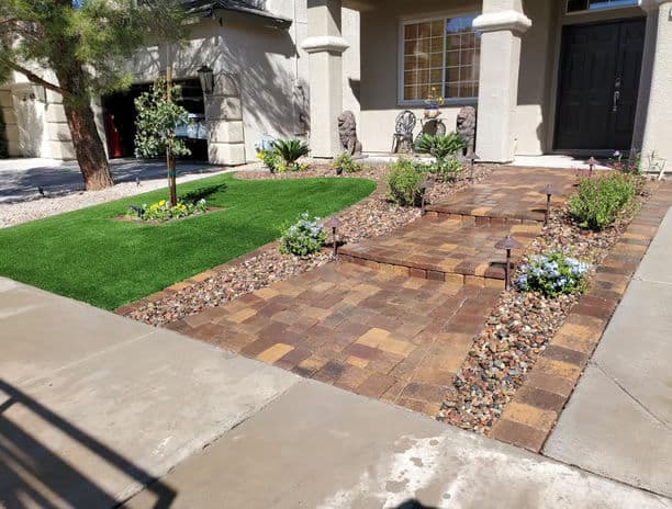 Beautiful landscaped front yard with stone pathway, decorative rocks, and greenery.